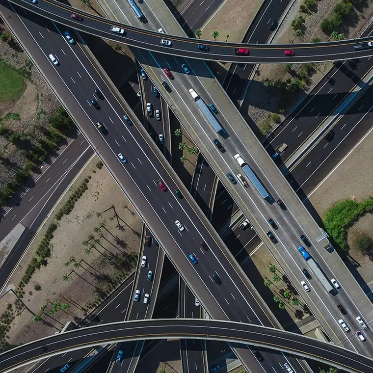 Entroncamento rodoviário visto de cima, com caminhões distribuídos pelas alças de acesso.